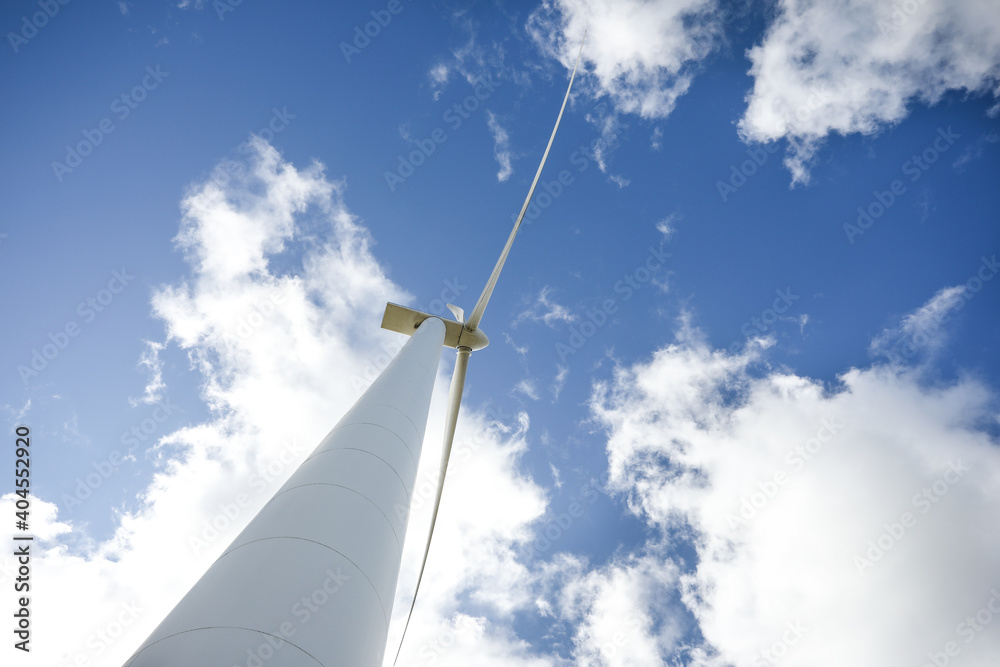 Wind turbine in a sunny day with blue sky and clouds. Wind farm eco field. Green ecological power energy generation. Wind turbine in a sunny day with blue sky and clouds. Wind farm eco field. Green ecological power energy generation.