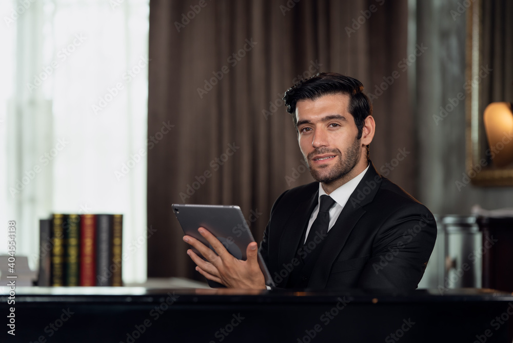 Portrait of young handsome confident businessman in suit using digital tablet Portrait of young handsome confident businessman in suit using digital tablet