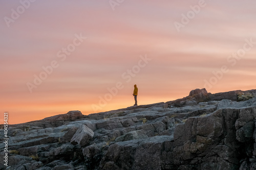 A silhouette, a figure on a steep cliff against the background of the sunset sky.
