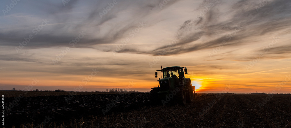 Fototapeta premium Tractor on the field during sunset.