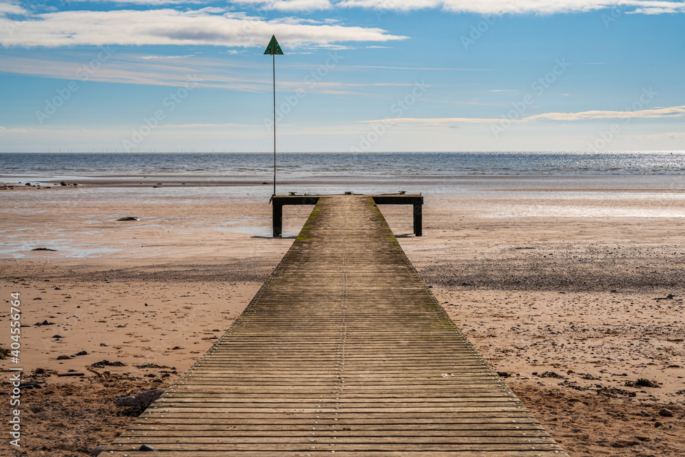 The beach and a wooden walkway in Seascale, Cumbria, England, UK