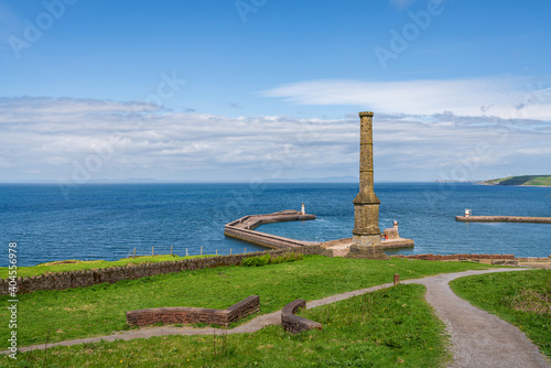 The Candlestick Chimney with the pier and the West Pier Lighthouse and North Pier Lighthouse in the background  seen in Whitehaven  Cumbria  England  UK