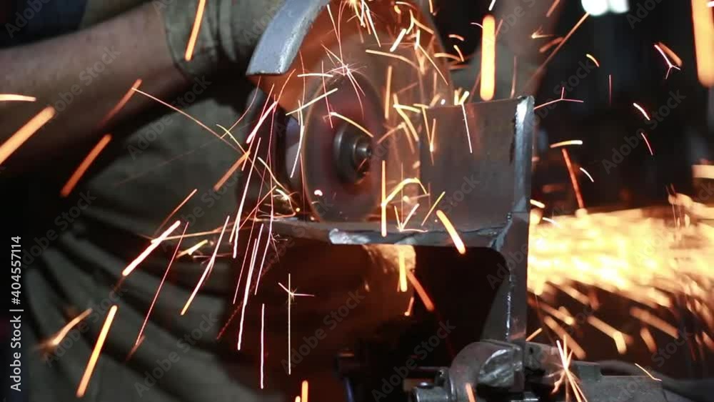 Metal processing with a grinder. The master grinds the steel. Sparks from the high friction of the grinder on the workpiece surface. Operation of a disk electric tool. 