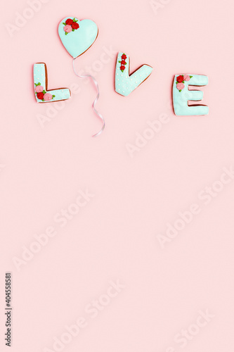 Word Love from homemade ginger biscuits and one in form heart flying as balloon, pink background. Valentines day Holiday sweet food concept.
