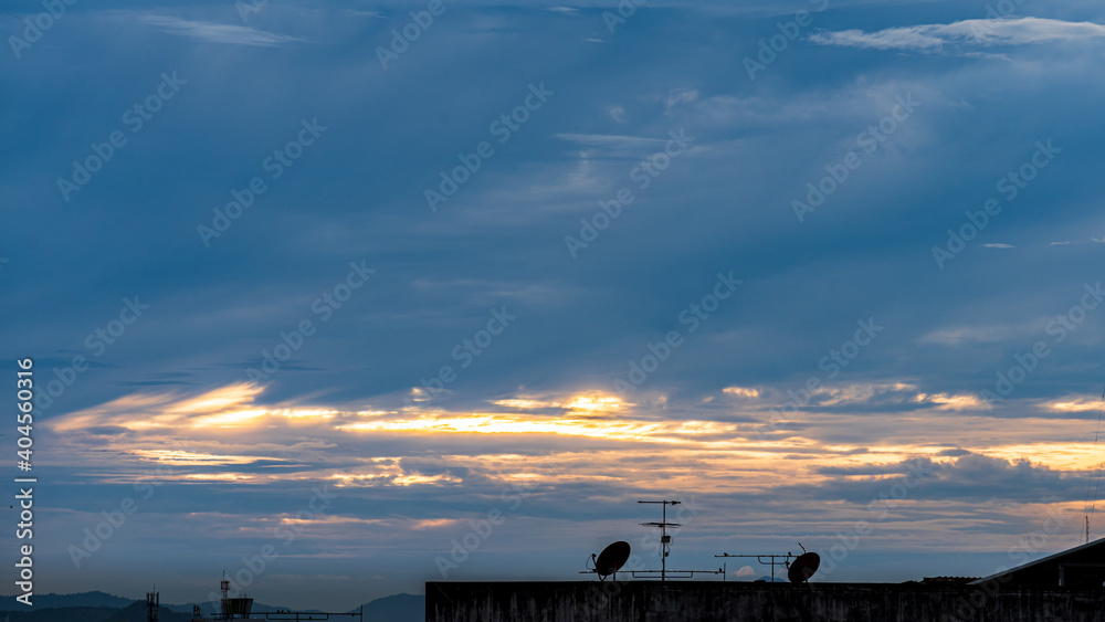A satellite dish on the roof of the house with clouds and sky as background