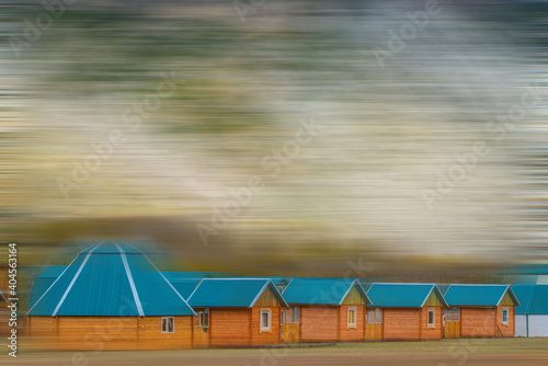 blurred view of wooden houses with blue roofs on green grass © photollurg