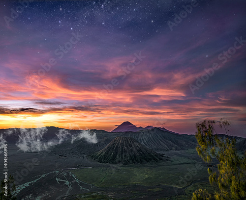 Beautiful sunrise with pink clouds and stars at a smoking mount Bromo volcano and mount Semeru in the background at East-Java, Indonesia