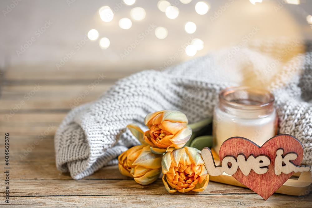 Cozy home composition love is for Valentine's Day with a candlestick, knitted element and flowers close up. Cozy home composition love is for Valentine's Day with a candlestick, knitted element and flowers close up.