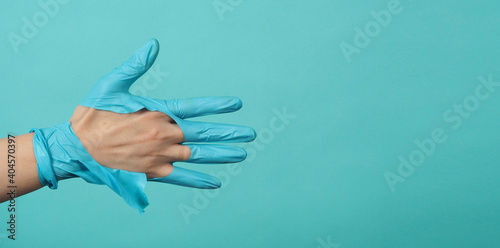 Close up of hand Wearing torn medical gloves or torn rubber gloves on blue and green or Tiffany Blue color background.monotone coclor. photo