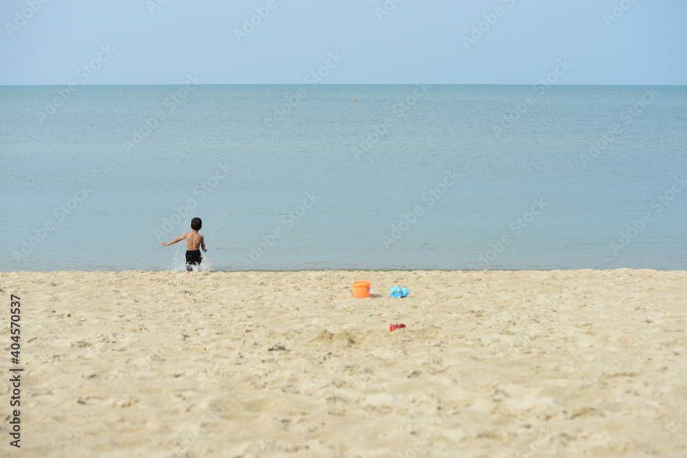 Obraz premium Children are having fun at the beach on a beautiful day, the sky is clear.