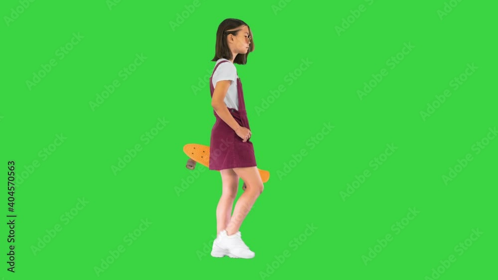 Girl holding a skateboard and walking on a Green Screen, Chroma Key. Girl holding a skateboard and walking on a Green Screen, Chroma Key.