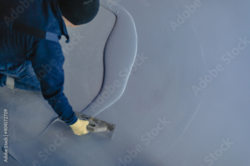 The worker applies gray epoxy resin to the new floor