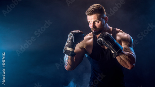 Sportsman boxer fighting on black background with shadow. Copy Space. Boxing sport concept. Smoke on background © zamuruev
