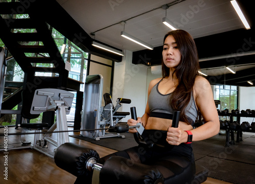 Young beautiful woman in sportswear working out with machine in gym