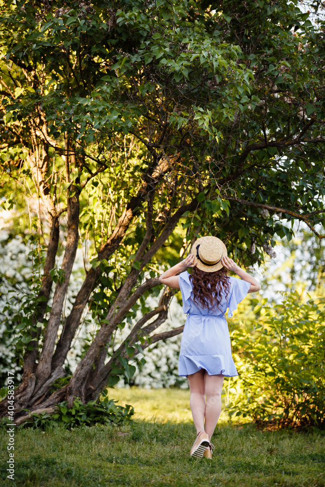 Summer mood. Romantic girl in Provence image and straw hat near beautiful tree. Spring or summer coming. Spring story. Brown-haired girl with long hairs.