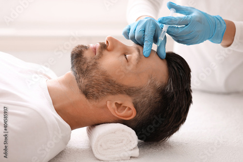 Plastic surgeon injecting hyaluronic acid in man forehead