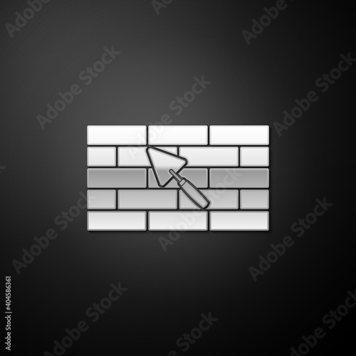Silver Brick wall with trowel icon isolated on black background. Long shadow style. Vector.