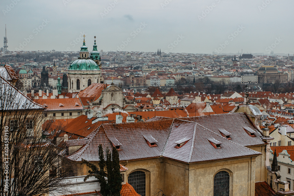 Postcard view of Old Town with historical buildings,red roofs,churches in Prague,Czech Republic.Prague winter panorama.Snowy day in the city.Amazing European cityscape cold weather.Romantic atmosphere