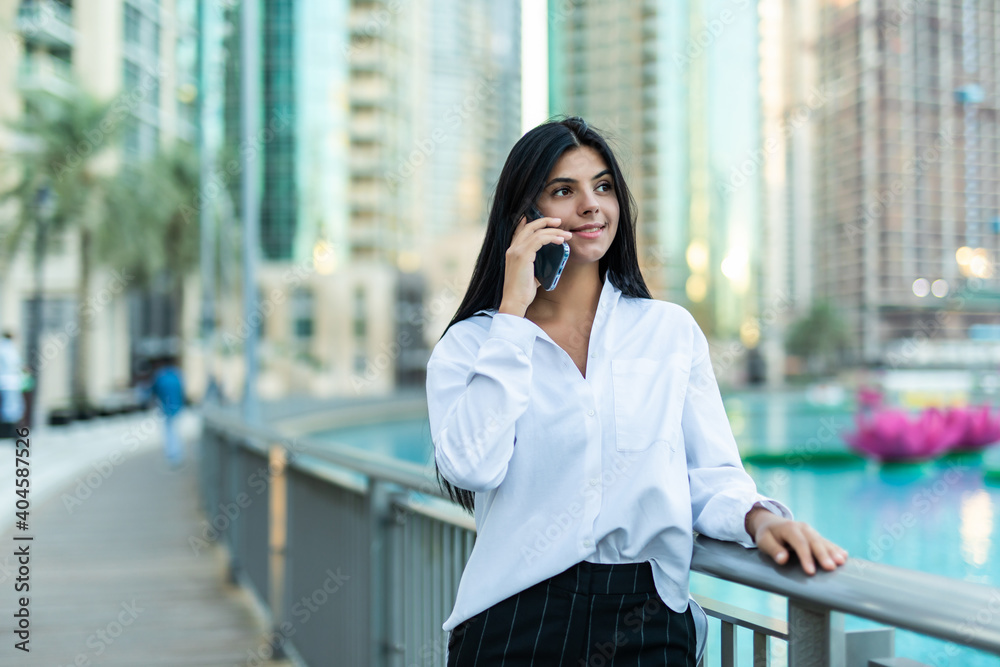 Fototapeta premium Successful businesswoman talking on cellphone while walking outdoor.