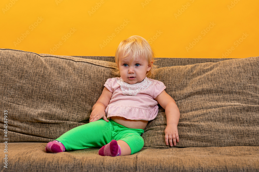 Fototapeta premium A business child is sitting on the couch and watching TV.