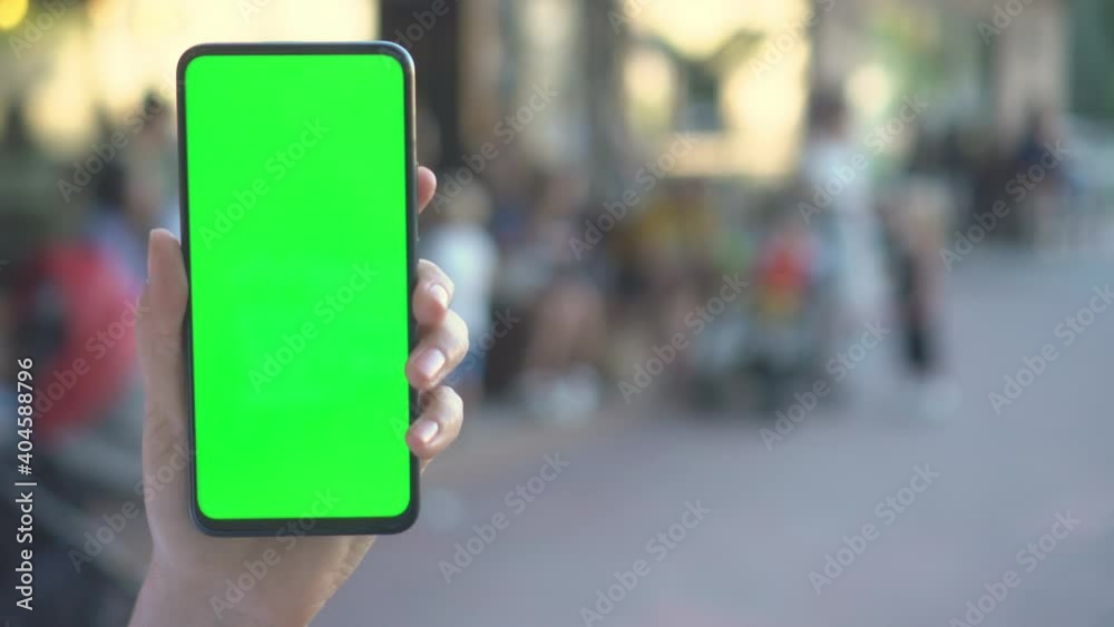 Close up hands woman holding phone with vertical green screen on busy ...