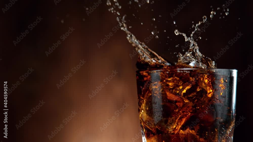 Super slow motion of falling ice cube into cola drink, camera movement. Filmed on high speed cinema camera, 1000 fps