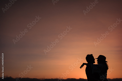 silhouette of a couple that looks at each other and hugs against the light in a sunset. Classic romantic image of a couple in love against a sunset background. Copy space Valentine s concept