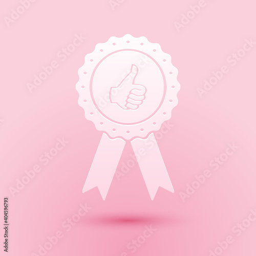 Paper cut Thumbs up on medal badge with ribbons icon isolated on pink background. Paper art style. Vector.