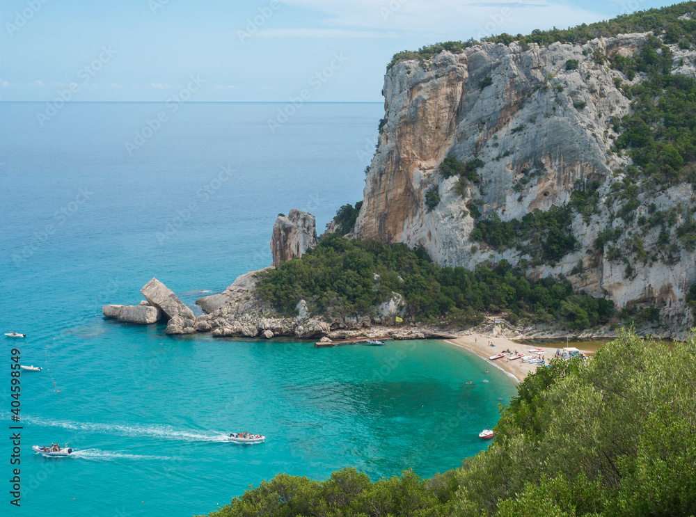 Aerial view of Cala Luna beach near Cala Gonone, Gulf of Orosei, Sardinia island, Italy. White sand beach with lime stone rocks and turquoise blue water. Famous travel touristic destination