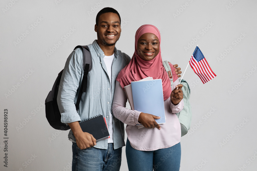Obraz na plátně Cheerful black muslim students couple holding american flag