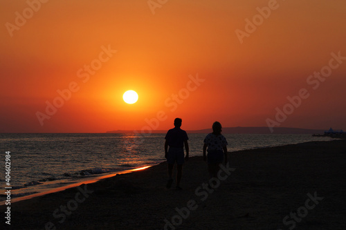 Silhouette Middle age couple walks along the coast at sunset