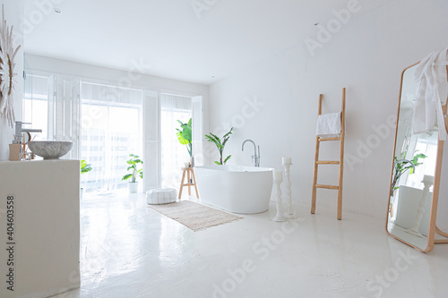 Extra white and very light minimalistic stylish elegant interior of bathroom with modern bath  green plants and wooden elements