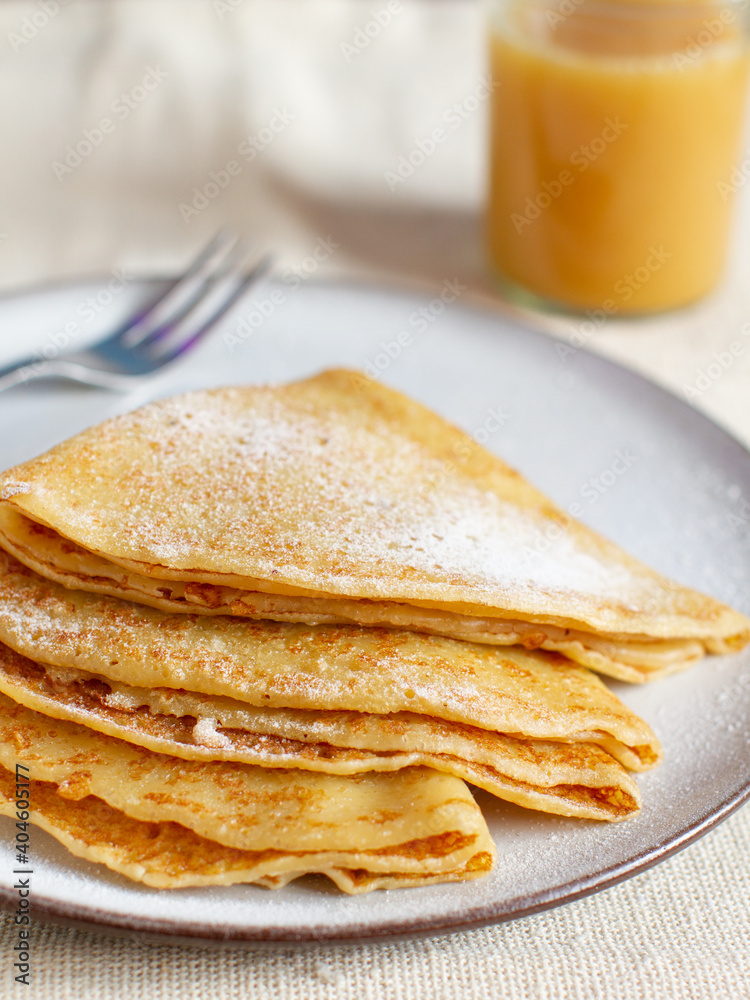 Stack of crepes with powdered sugar on a table. Pancakes for breakfast. Stack of crepes with powdered sugar on a table. Pancakes for breakfast.