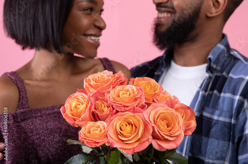 Pair of sweethearts holding beautiful bouquet of roses for Valentine's Day over pink studio background, selective focus