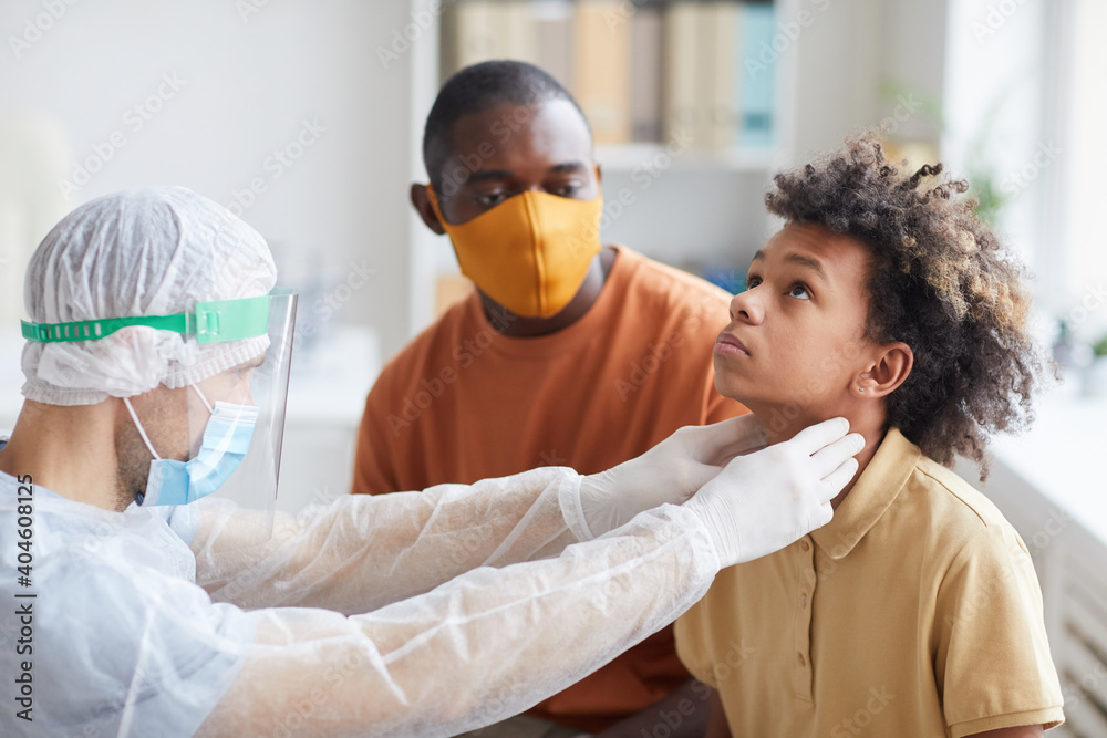 Φωτογραφία Portrait of male doctor examining African-American boy and palpating throat duri