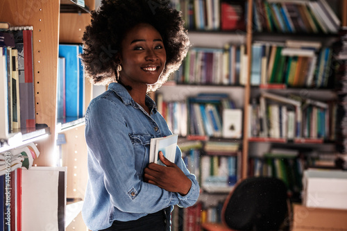 Portrait of young black female student .She standing in college library.	
