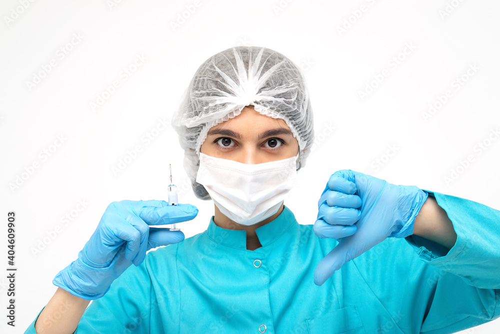 Medical worker in protective clothing,gloves and mask holding a syringe and showing the thumb down sign.Medicine and healthcare concept.Coronavirus vaccination concept. Medical worker in protective clothing,gloves and mask holding a syringe and showing the thumb down sign.Medicine and healthcare concept.Coronavirus vaccination concept.