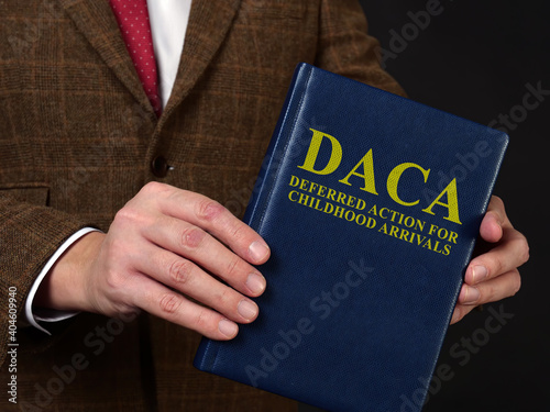 Deferred Action for Childhood Arrivals DACA concept. Man in suit shows the book. photo