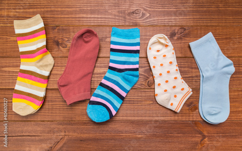 multicolored new socks in different sizes stacked on a wooden background. clothes for women