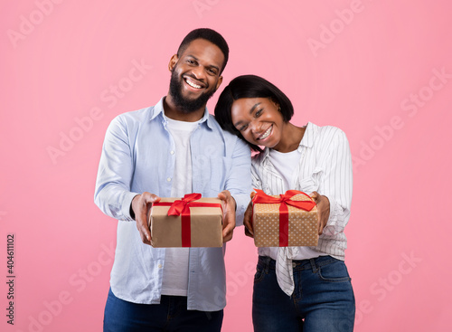 Portrait of Valentine sweethearts with gift boxes celebrating holiday together on pink studio background