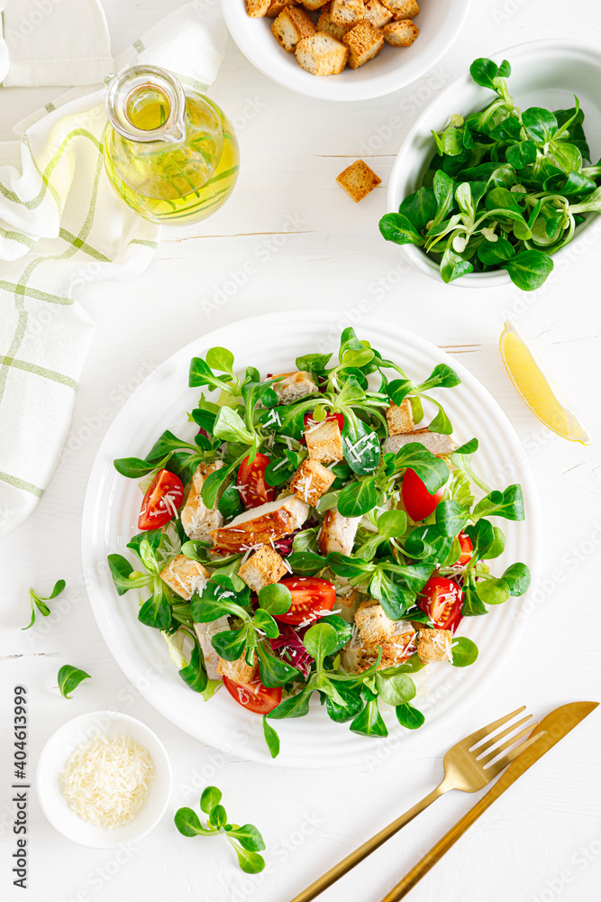 Caesar salad with grilled chicken meat, fresh tomato, croutons, lambs lettuce and parmesan cheese. Healthy lunch. Top view Caesar salad with grilled chicken meat, fresh tomato, croutons, lambs lettuce and parmesan cheese. Healthy lunch. Top view