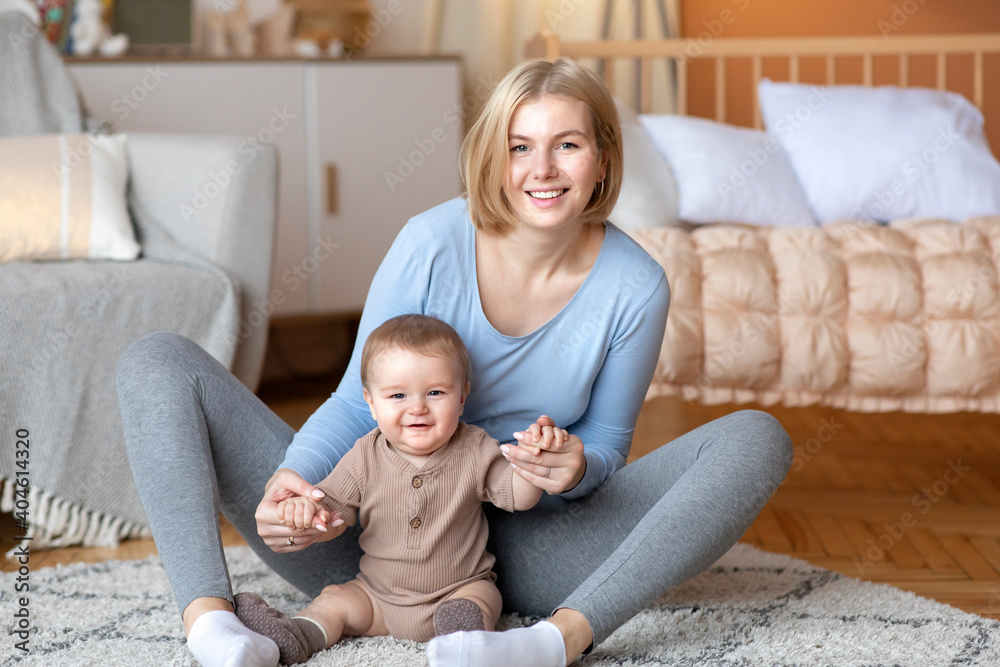 Mother playing with her infant child, sitting on bed Mother playing with her infant child, sitting on bed