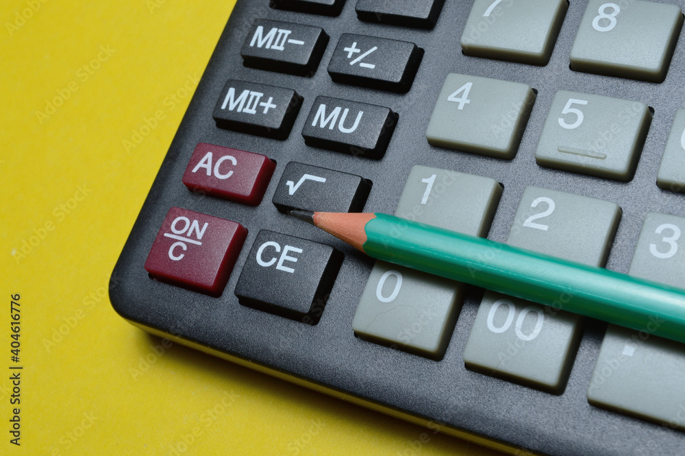calculator and pencil lie on a yellow background. close-up.