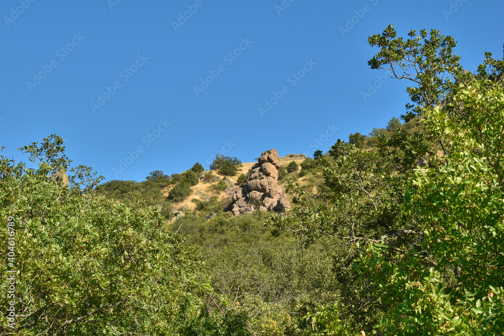 A pile of stones of unusual shape on the slope of a green hill
