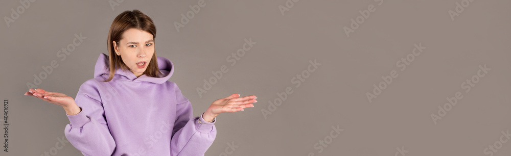 Portrait of a pretty woman shrugging shoulders isolated on a gray background Portrait of a pretty woman shrugging shoulders isolated on a gray background