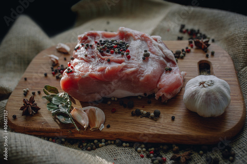 Uncooked piece of fresh meat with peppercorn and garlic on the wooden cuttig board and burlap  photo