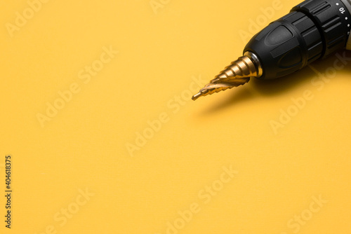 Step conical drill bit on the yellow background close up.