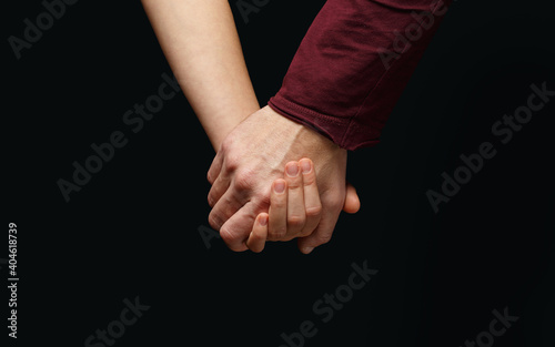 Male hand holds female hand on dark background