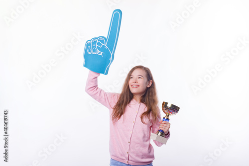 Cheerful winner girl is holding a trophy and foman fan glove over white background. photo