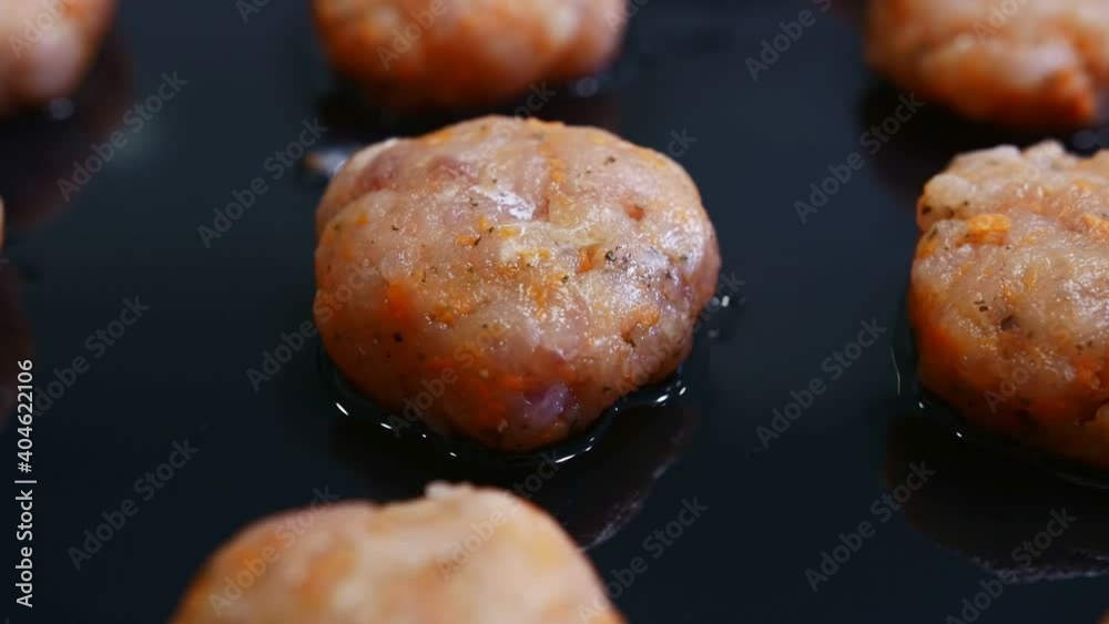 Close-up of balls of minced fish lie on a black metal baking sheet. Close-up of balls of minced fish lie on a black metal baking sheet.
